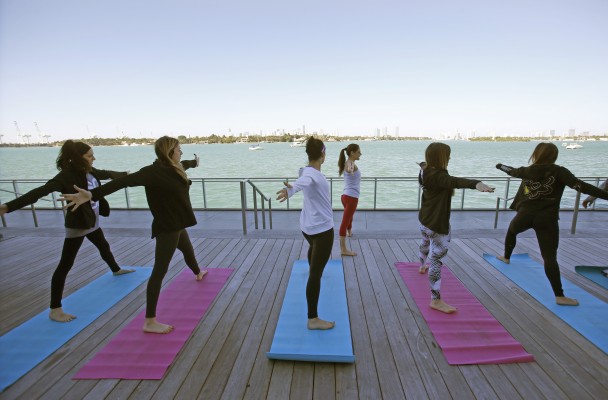 In this Jan. 24, 2016, photo, Paula Walker, background center, an instructor with Green Monkey Yoga, leads a yoga class at the Mondrian South Beach Hotel in Miami Beach, Fla. The hotel world is moving beyond basement gyms and ho-hum spa menus to accommodate guests growing requests to stay healthy while on the road. The number of hotels with fitness facilities jumped from 63 percent in 2004 to 84 percent in 2014, according to the American Hotel & Lodging Association. (AP Photo/Wilfredo Lee)