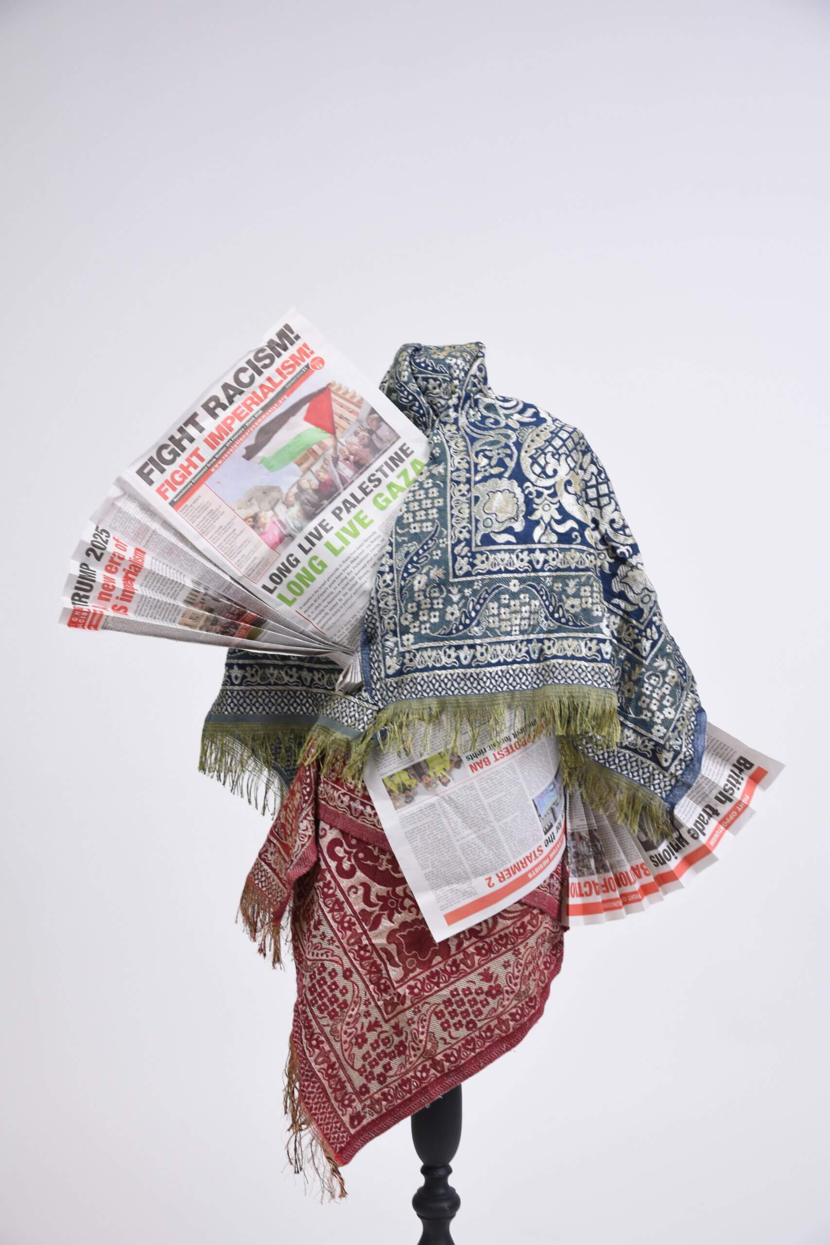 Textile draped over mannequin with newspaper titles